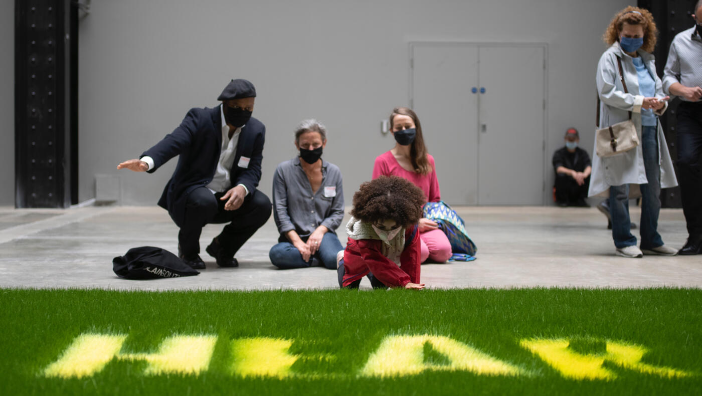family sit in front of grass installation at Tate Modern