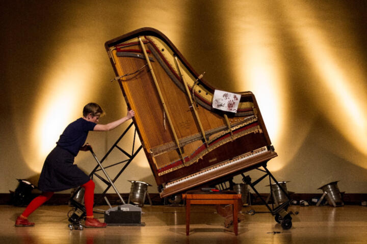 woman pushes piano during a performance