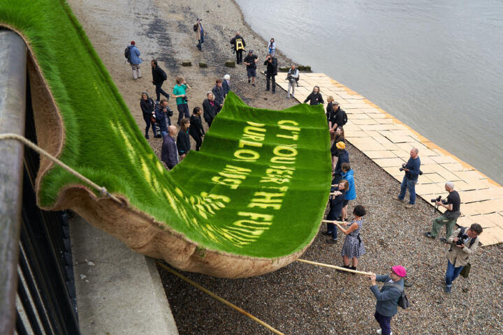 a group of artist handle a huge grass banner