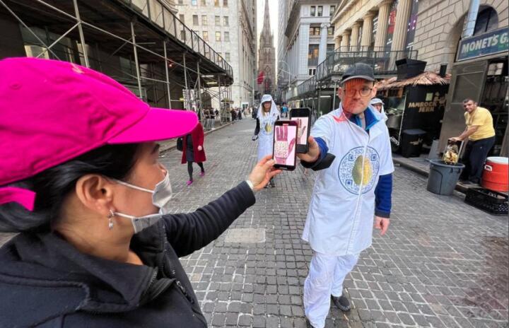 A peson uses their phone to to capture a photo off anothers phone on the streets of New York