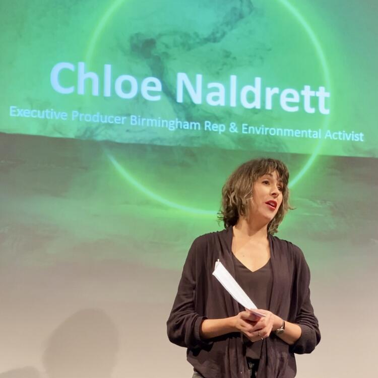 Chloe Naldrett standing in front of a screen that reads "Chloe Naldrett, Executive Producer Birmingham Rep & Environmental Activist